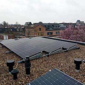 Een installatie van zonnepanelen op een schuin dak met grind, met meerdere panelen helder zichtbaar.
