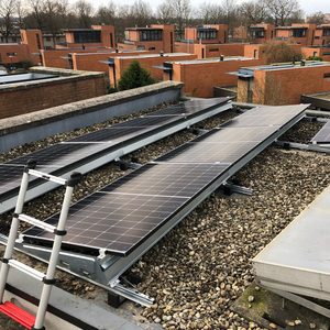 Een installatie van zonnepanelen op een plat dak, voorzien van een antislip ondergrond van grind.