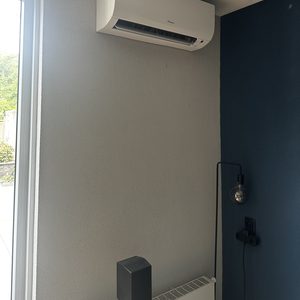 Een wandmodel airconditioning unit, efficiënt voor het koelen van ruimtes. Geïnstalleerd boven de radiator in een moderne inrichting.