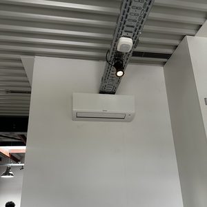 Installeer een wandmodel airconditioningseenheid in een moderne ruimte met zichtbare plafondinrichting.