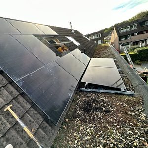Een installatie van zonnepanelen op een hellend dak, met een Arbeider die bezig is met de montage.