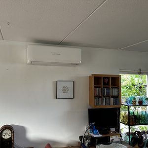 Een wandairconditioner geïnstalleerd in een woonruimte, met een overzicht van meubels en decoratie.