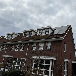 De foto toont een dak met zonnepanelen geïnstalleerd op een woning, wat duidt op duurzame energieproductie.