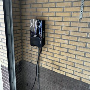 De afbeelding toont een wandgemonteerde laadpaal, geschikt voor het opladen van elektrische voertuigen, met een duidelijke en nette afwerking.
