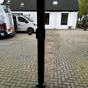 Een laadpaal installatie in een oprit, zichtbaar met een servicemiddel en een huis op de achtergrond.