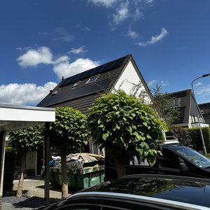 Een woning met zonnepanelen op het dak, duidelijk zichtbaar en goed geïnstalleerd onder een heldere lucht.