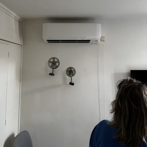 De afbeelding toont een wandgemonteerde airconditioner in een binnenruimte, ideaal voor klimaatbeheersing.