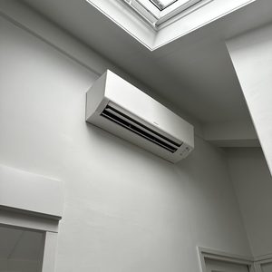 Een wandairco-installatie geplaatst aan een muur, met een ladder eronder voor toegang.