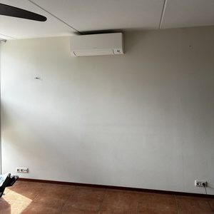 De afbeelding toont een wandmodel airconditioner geïnstalleerd aan een muur, met een strak en modern ontwerp.