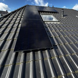 De foto toont zonnepanelen die zijn geïnstalleerd op een hellend dak, met een heldere lucht op de achtergrond.
