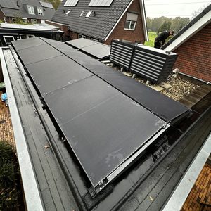 Deze installatie toont zonnepanelen op een plat dak, met de panelen netjes uitgelijnd en geconfigureerd voor maximale zonlichtopvang.