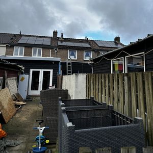 De afbeelding toont zonnepanelen die zijn geïnstalleerd op het dak van een woning, met een zicht op de achtergrond van de omgeving.