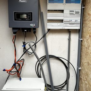 Installatie van een omvormer en meterkast voor zonnepanelen, met bekabeling zichtbaar.