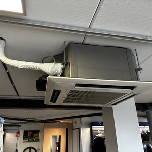 Een luchtverdeelunit voor airconditioning is geïnstalleerd aan het plafond, met een afvoerbare luchtkanalensysteem.