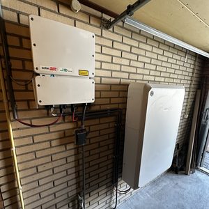 De afbeelding toont een installatie van een thuisbatterij gecombineerd met omvormers, bedoeld voor energieopslag uit zonnepanelen.