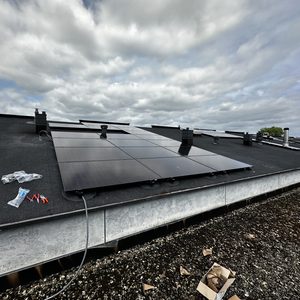 Een set zonnepanelen geïnstalleerd op een plat dak, met zichtbare montagematerialen en bekabeling. Goede blootstelling aan zonlicht.