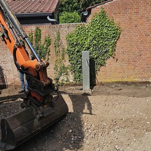 De foto toont een bouwlocatie waar voorbereidingen worden getroffen voor de installatie van zonnepanelen, met een graafmachine en een constructieelement in beeld.