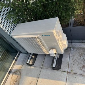 Externe unit van een Daikin airconditioningsysteem, ontworpen voor koeling en verwarming, geplaatst op een stevige basis.
