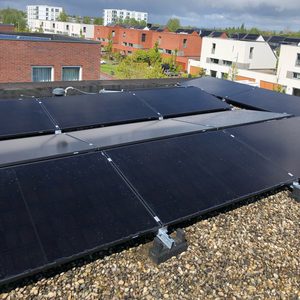Deze foto toont een installatie van zonnepanelen op een plat dak, met meerdere panelen zichtbaar in een stedelijke omgeving.