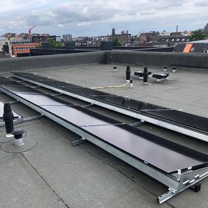 Deze afbeelding toont een installatie van zonnepanelen op een plat dak, gericht op het opwekken van zonne-energie.