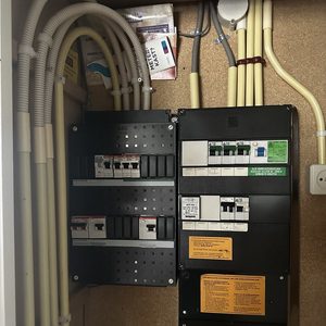 De afbeelding toont een meterkast met elektrische schakelaars en bekabeling, essentieel voor de elektriciteitsverdeling in een huis.