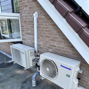 Installatie van een wandunitsysteem voor airconditioning met buitenunits en leidingen, geschikt voor temperatuurregeling.