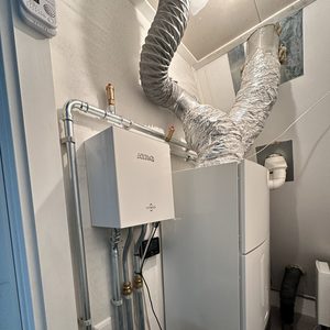 De installatie toont een warmtepomp met leidingen en een opslagtank, die samen zorgen voor verwarmingsoplossingen in een woning.