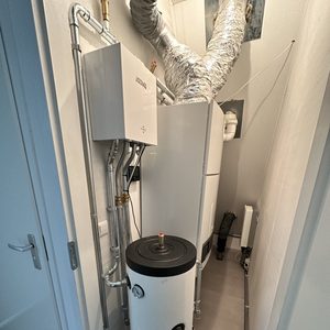 De foto toont een warmtepompinstallatie met een gecombineerde eenheid en opslagtank in een technische ruimte.