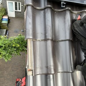 De afbeelding toont een zonnepaneleninstallatie op een dak, met een installateur die bezig is met de montage.