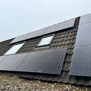 Een installatie van zonnepanelen op een hellend dak, gericht op duurzame energieoplossingen voor woningen.