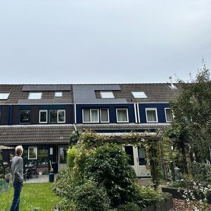 De afbeelding toont een woning met zonnepanelen op het dak, geïnstalleerd voor hernieuwbare energieoplossingen.