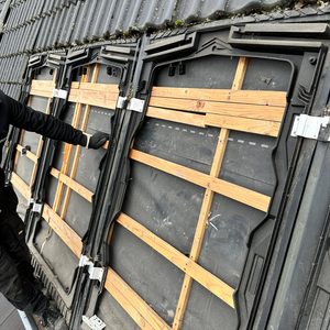 De afbeelding toont een laadpaal installatie met de montagematerialen en een technicus aan het werk.
