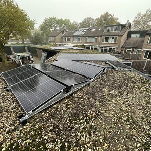 De installatie toont zonnepanelen op een schuin dak, bevestigd met metalen steunen. De omgeving is slecht zichtbaar door mist, maar het installatieproces lijkt gaande.