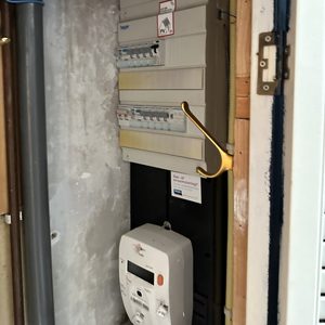 De afbeelding toont een meterkast met elektriciteitsmeters en bekabeling, belangrijk voor de aansluiting van zonnepanelen, maar de zonnepanelen zelf zijn niet zichtbaar.