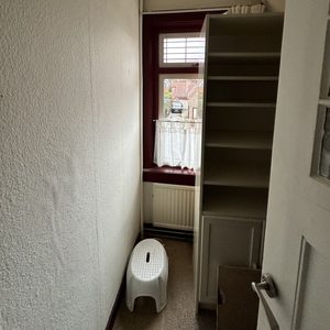 De foto toont een ruimte waarin zonnepanelen worden geïnstalleerd, met zicht op een raam en een kleine witte voetensteun. Er zijn geen zonnepanelen zichtbaar.
