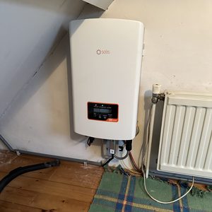 De foto toont een Solis omvormer, een essentieel onderdeel van een zonnepaneleninstallatie, bevestigd aan de muur.