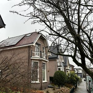 Zonnepanelen zijn geïnstalleerd op het dak van een woning, zichtbaar in een stedelijke omgeving met een dreigende lucht.