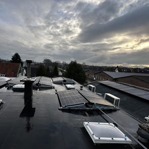 De foto toont een installatie van zonnepanelen op een plat dak, met meerdere panelen uitgelijnd om optimale zonne-energie te verzamelen.