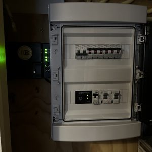 De afbeelding toont een meterkast met een Enphase omvormer, die verbinding maakt met de zonnepaneleninstallatie.