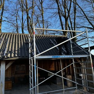Een installatieproject voor zonnepanelen op het dak, met steigerwerkzaamheden in uitvoering en voorbereidende elektrische aansluitingen.