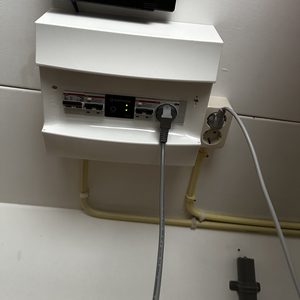 De afbeelding toont een deel van een meterkast met een Enphase apparaat en bekabeling, wat wijst op een installatie gerelateerd aan zonnepanelen.