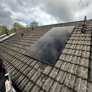 De foto toont een installatie van zonnepanelen op een hellend dak, met een duidelijk zicht op de panelen en de dakbedekking.
