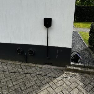Een laadpaal is geïnstalleerd aan de muur van een woning, geschikt voor het opladen van elektrische voertuigen.