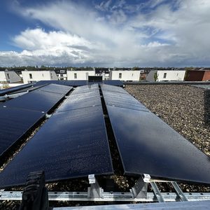Een installatie van zonnepanelen op een plat dak, zichtbaar met waterdruppels, wat aangeeft dat ze recent zijn gereinigd of dat het geregend heeft.