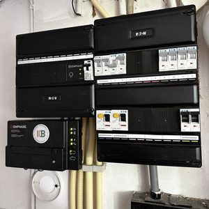 De afbeelding toont een meterkast met verschillende schakelaars en een Enphase omvormer, essentieel voor een efficiënte energieverdeling.