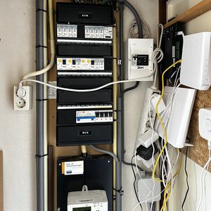 De afbeelding toont een meterkast met elektrische aansluitingen en bedradingssystemen, typisch voor laadpalen installaties.