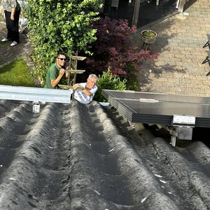 Installatie van zonnepanelen op een dak, met werkende personen die de panelen aanbrengen.
