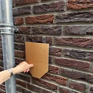 De installatievoorbereiding voor een laadpaal, zichtbaar door de sjabloon op de muur, laat zien waar de laadpaal bevestigd zal worden.