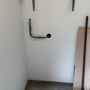 De afbeelding toont een wand met een voorbereidende installatie voor een laadpaal, inclusief een behuizing en leidingen.