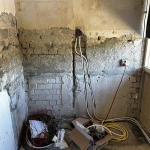 De foto toont een onvoltooide wand met elektrische bekabeling en installatie benodigdheden, wat kenmerkend is voor een meterkast of elektrische installatie voorbereidingen.